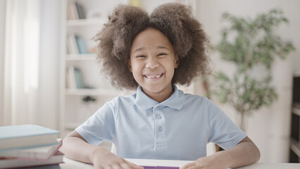 Cute positive girl with curly hair smiling on camera, child's teeth, dental health