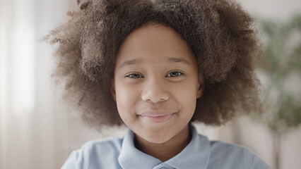 African american curly-haired child attentively looking at camera and smiling