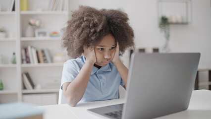 Bored school pupil doing exercise online, typing on laptop at home, lockdown
