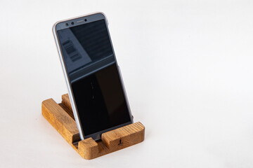 Smartphone on handmade wooden stand, isolated on white background