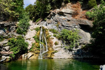 Cascade and deep pool with clear, emerald-green water for swimming in river Bucatoggio, Moriani-Plage. Corsica, France.