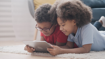 Cute kids playing games on tablet, using online application for entertainment