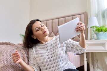 Middle aged woman with closed eyes waving a magazine in a state of fever
