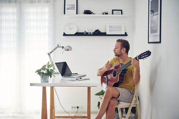 Man playing acoustic guitar at home.