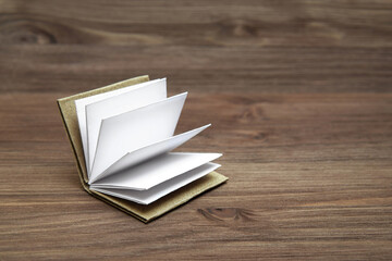 Open miniature book on a wooden background