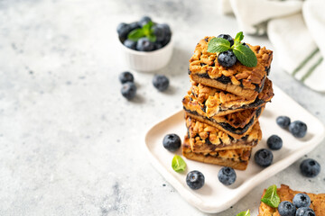 Shortbread bar cookies with blueberries on a serving plate on a light gray kitchen table. Delicious homemade sweet pastries