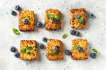 Shortbread bar cookies with blueberries are spread out  on a light gray kitchen table. Delicious homemade sweet pastries	
