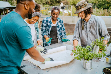 Smiling male and female farmers discussing at table in community garden