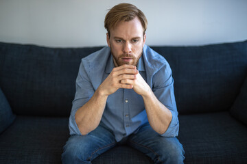 Man at home feeling sad and depressed sitting on a couch