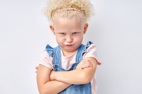 Naughty caucasian child. Disobedience problem. Discipline punishment. Portrait of angry offended little girl in shirt dress with crossed arms isolated on white copy space background.