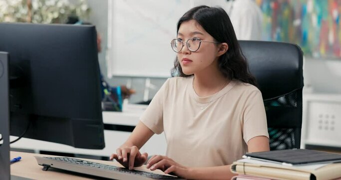 Nerd girl in big glasses and tshirt sits in comfortable chair in front of desk, taps fingers on computer keyboard, sends messages, emails, writes back, runs company website, office life, corporate