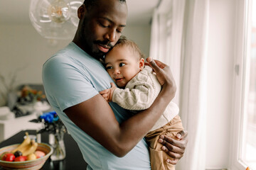 Father carrying baby boy at home