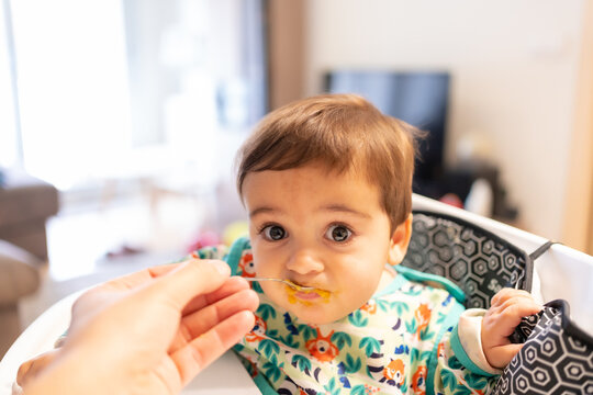 Father Feeding His Baby Solid Food, His First Vegetable Purees, First Person View Of The Father Feeding Him Spoonfuls At Home