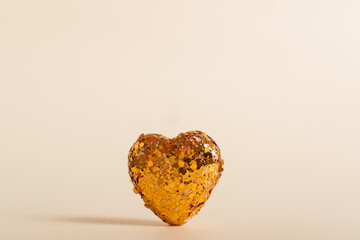 A heart made of sequins on a beige background. A heart of copper sequins develops on a beige background. Valentine's Day greeting card. Banner for February 14. copywriting