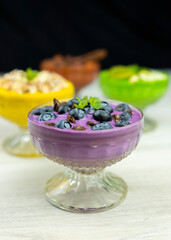 Smoothie or pudding with blueberries and chocolate served in a bowl for breakfast with several other smoothies in background