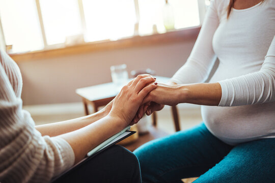 Pregnant woman on home counselling meeting. You're not in this alone. Depressed pregnant woman consultation with psychologist. Psychiatrist holding hands patient,such as making a fresh start