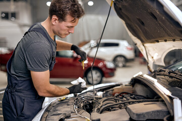 caucasian young mechanic in uniform doing car service and maintenance. Oil and fuel filter...