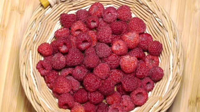 Fresh juicy red raspberries in a backet rotation. Close up