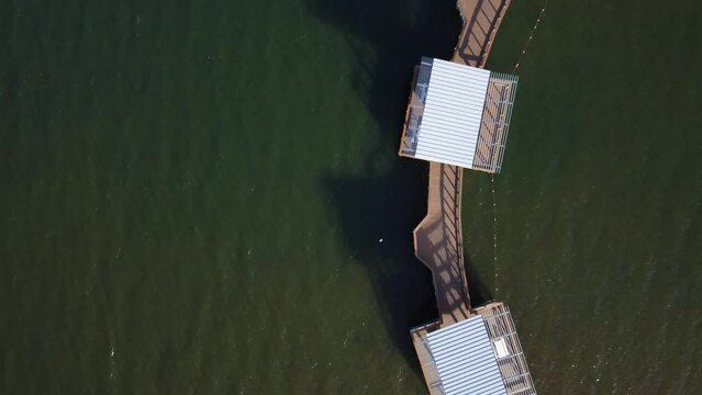 Top down view of curving fishing pier on Lake Wylie in South Carolina, USA. Slow drone flyover.