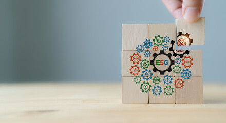 ESG concept of environmental, social and governance. Sustainable corporation development. Hand holds wooden cubes with ESG target icon  standing with other ESG icons on grey background. Copy space.