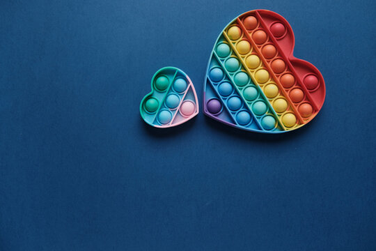 Two romantic hearts touch side by side. Silicone colorful anti-stress toy on a blue background. Click the pop up bubble, a simple dimple toy. The concept of romance, love, gift, valentine's day, holid