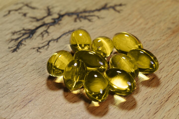 Fish fat cod liver oil omega gel capsules on wooden background