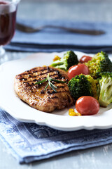 Grilled Turkey Breast with oven baked broccoli, cherry tomatoes and sweet corn. Bright  wooden background. Close up. 