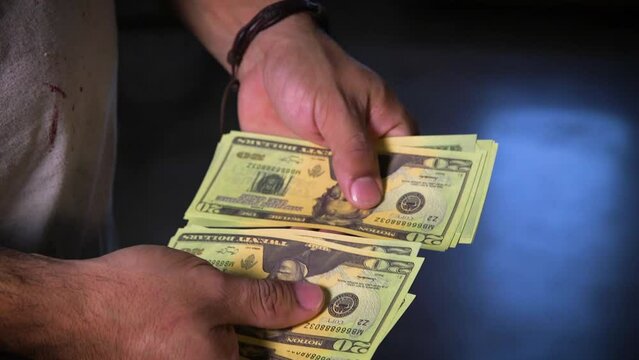 Hispanic male counting U.S. currency dollar bills notes money.