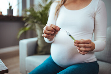 Unrecognizable pregnant woman with syringe in hand. Woman making hormonal therapy injection into...