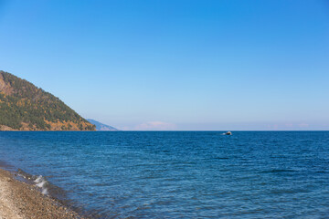 Blue calm sea and white clouds. Snow capped mountains on the horizon.