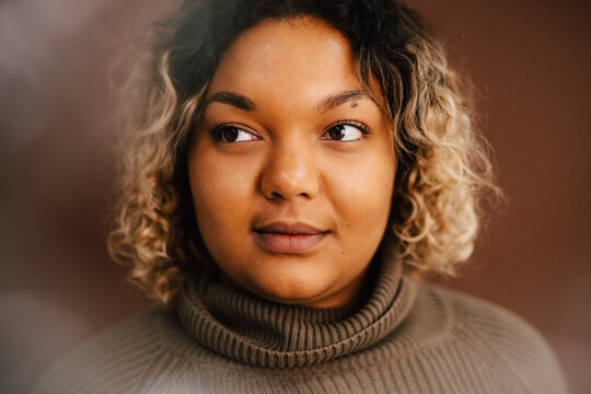 Contemplative woman over brown background in studio