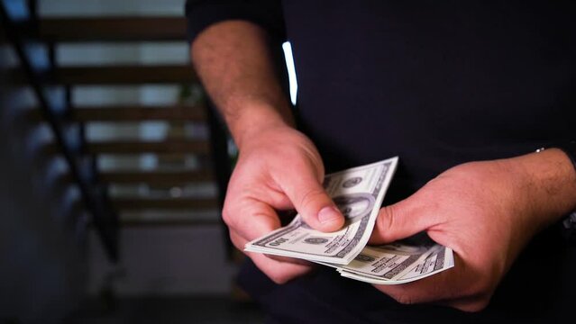 Hispanic male counting U.S. currency dollar bills notes money.