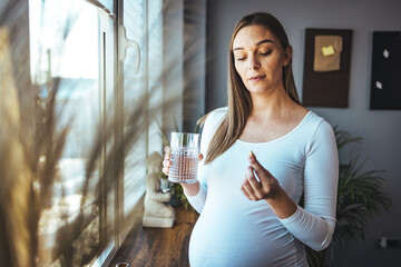Beautiful pregnant woman taking pills for morning nausea. Close-up Of Pregnant Woman Hand With...