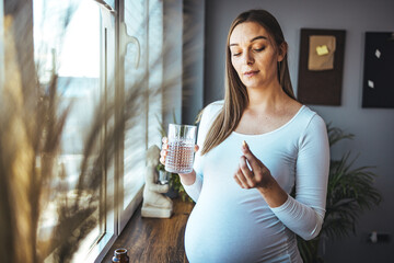 Happy woman holds pill glass of water, takes daily medicine vitamin D, omega 3 supplements, skin...