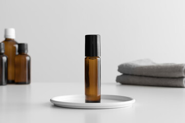 Amber glass roll-on bottle mockup with a towel on the white table.