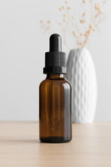 Dropper bottle mockup with a gypsophila on the wooden table.