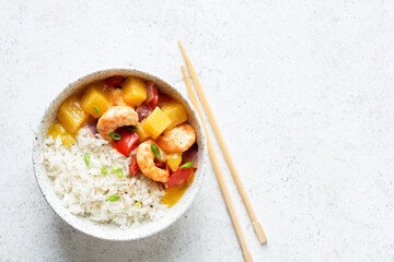Pineapple shrimp curry with rice in bowl on light grey background, top view copy space. Asian...
