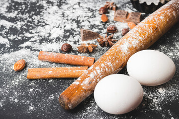 Baking concept, rolling pin, eggs, cupcake form and food ingredients on a dark background, prepare for cooking