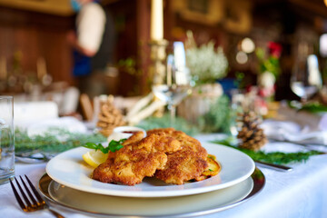Sehr leckeres Wiener Schnitzel mit Krosser Panade und Bratkartoffeln und Preiselbeer serviert in einem Restaurant Wirtshaus