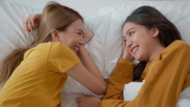 Homosexual lesbian couple lying in bed with their heads close together. Woman and female share love, face each other, smile warmly at each other. Gay family. LGBTQ Pride Month, Couple Equality Concept
