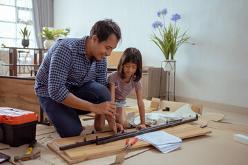asian father and daughter assembling new furniture at their home