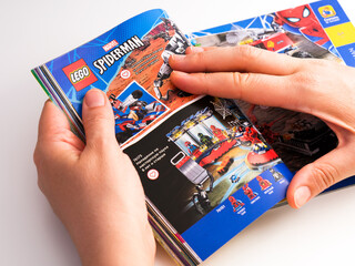 Obraz premium Tambov, Russian Federation - December 21, 2021 Woman browsing Lego catalog on a page with Lego Spider-Man sets.