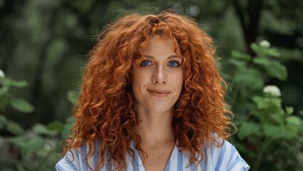 pretty redhead woman with blue eyes smiling outside.