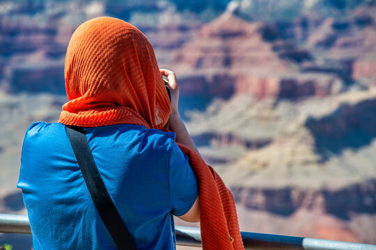 Woman wiearing colorful clothes taking pictures of South Rim in Grand Canyon National Park, USA.