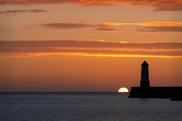 Sunrise behind the light tower at the entrance of Berwick upon tweed harbour