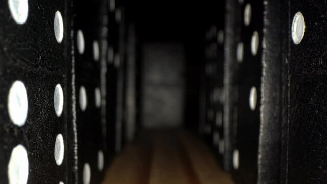 Macro close up of a video drive between rows of dominoes on a wooden board, zero stone at the end of the line