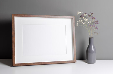 Landscape wooden frame mockup for artwork, photo and print presentation with dry flowers in vase....