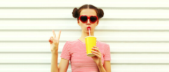 Portrait of young woman drinking fresh juice wearing striped t-shirt with cool hairstyle on white background