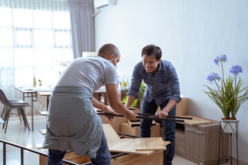 two male woodworker assembling new furniture together