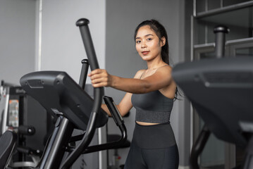 Fototapeta na wymiar Asian woman exercises in fitness. Young healthy woman in sportswear is cardio exercises in gym.